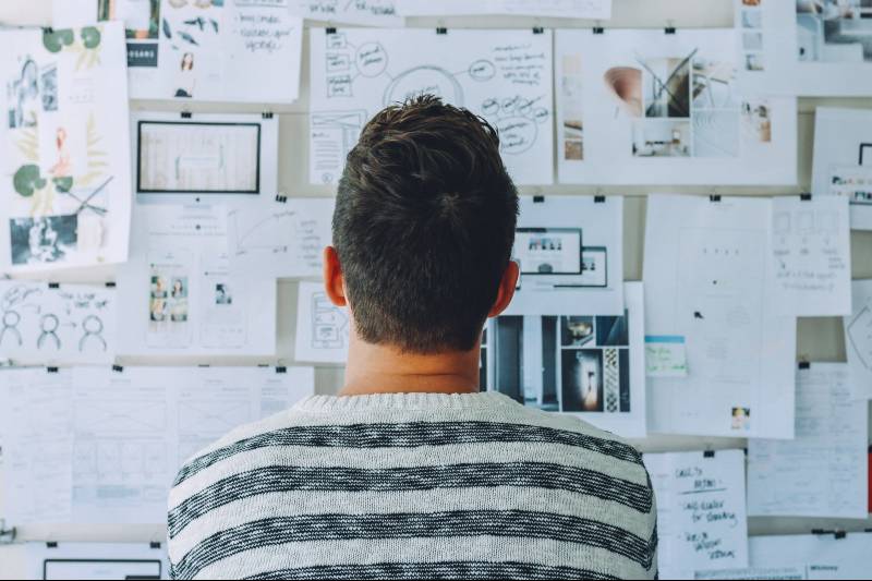 man looking at a noticeboard with lots of papers pinned to it